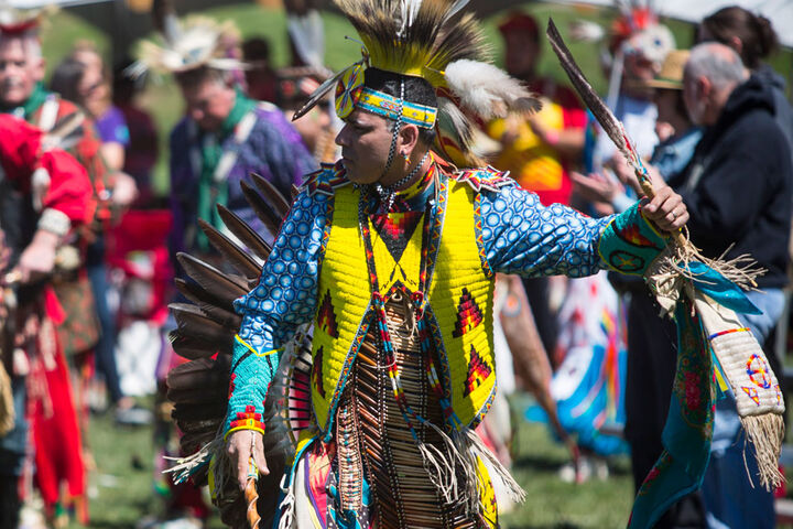 A Native American wearing traditional attire at a powwow.